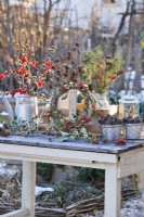 Winter display with wreath of mistletoe and guelder rose, bunches of pine, larch, pussy willow and guelder rose twigs in milk churns and in watering can.