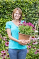Woman holding a terracotta pot planted with a pink Chrysanthemum