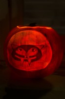 Halloween carved and decorated pumpkin lantern depicting a scary animal face.  October