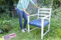 Woman using stripping knife to remove old paint from the chair