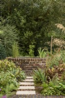 Raised circular brick pond in a garden in September