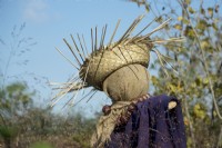 Friendly scarecrow with straw hat and purple blanket. Necklace of chestnuts.