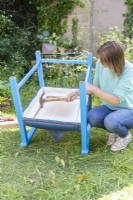 Woman using hammer to remove base seat base from chair