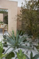 An outdoor dining area surrounded by Mediterranean plants in the Hamptons Mediterranean Garden, a sanctuary garden designed by Filippo Dester at the RHS Chelsea Flower Show 2023

