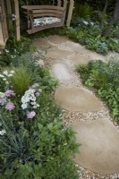 The London Square Community Garden. Design: James Smith Sanctuary Garden: RHS Chelsea Flower Show 2023. Natural stone and gravel pathway through borders to seating area. Summer.