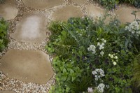 Natural stone and gravel pathway through border. Summer.