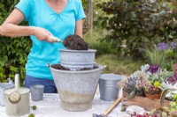Woman filling buckets with compost and stacking them to create a tiered effect
