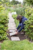 Woman placing stone pavers on path