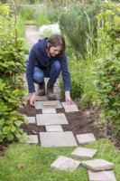 Woman placing stone pavers on path