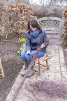 Woman using wire to bind birch twigs together to create a garland