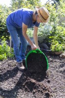 Woman adding compost over the area where the herbs will be planted