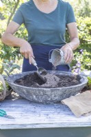 Woman mixing grit in with the compost in the shallow container