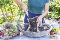 Woman filling hessian and chicken wire funnel with compost