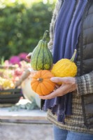 Woman holding three different coloured squashes