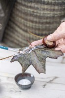 Woman glueing the maple leaves to the sticks to look like wings