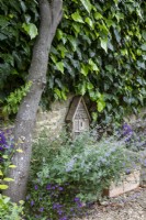 insect house stands on a stone seat against the Cotswold stone wall, flanked by Nepeta 'Six Hills Giant' and a self-seeded campanula
that grows out of several walls through the garden. This area is shaded by an Amelanchier lamarckii.