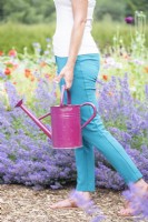 Woman walking through garden carrying a watering can