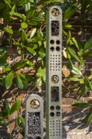Modern insect house set against brick wall in walled garden