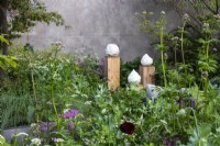 Ceramics by Gregory Tchalikian surrounded by planting on the RBC Brewin Dolphin Garden designed by Paul Hervey-Brookes - RHS Chelsea Flower Show 2023