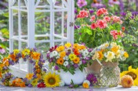 Display of  summer flower wreaths and bouquets made of hydrangea, sunflowers, cosmos, coneflowers, nasturtium, pot marigold, achillea, love in the mist and red clover.