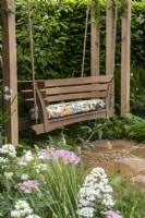 A swing seat enclosed by planting on The London Square Community Garden - Sanctuary Gardens - Designer James Smith - RHS Chelsea Flower Show 2023