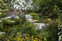 A view across wildlife friendly planting towards a secluded seating area on The RSPCA Garden designed by Martyn Wilson - RHS Chelsea Flower Show 2023