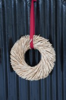 Christmas wreath made from straw and hung using red ribbon