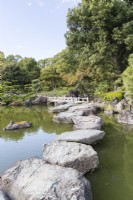 Stepping stones arranged at the lakes edge known as Iso-watari with view to wooden bridge