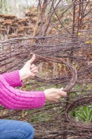 Woman weaving birch sticks in a circle to help hold open the bird perch