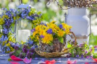 Spring bouquet containing grape hyacinth, viola and dandelion in tea pot made of bark, willow and lichens.