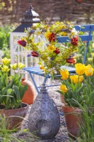 Tulips in terracotta pots and heart shaped wreath made of tulips, daffodils, muscari and golden Japanese Euonymus.