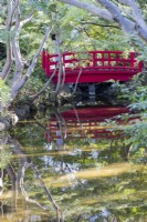 Red painted wooden bridge over the Seisen pond,reflected in the water. 