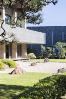 Raked gravel with placed rocks known as karesansui with pine trees in area called the Stone garden. View to the hotel. 