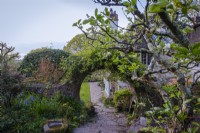 View through circular brick arch to the house and front lawn at Greencombe Gardens, Devon