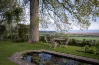 View across formal pond in country garden, towards the sea