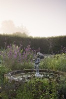 Cherub statue in a circular pond in the herb garden at Parham House in September