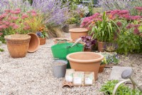 Narcissus 'Hawera', Crocus sieberi 'Tricolor' and Hyacinthus 'Delft Blue' bulbs in brown paper bags, large terracotta container,  bucket of grit and a trug of compost laid out on the ground