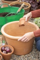 Woman placing crocks in large terracotta container