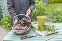 Woman mixing grit and compost together in trug