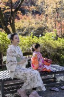 Mother and daughter wearing traditional dress seated in the valley garden. 