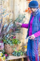 Woman placing Eucalyptus sprigs in wicker basket