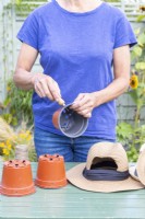 Woman using bradawl to poke holes in the plastic pots