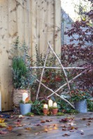 Light up Birch star, Candles, Cotoneaster, trug of Ivy, metal pot of Rosehips, wicker basket containing Juniper, Eucalyptus sprigs and Cornus twigs with moss placed around and leave scattered across the deck