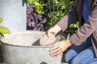 Woman placing large pebbles in metal basin