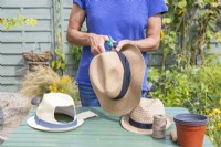 Woman cutting holes in the back of the hats to create space for the plant