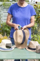 Woman cutting holes in the back of the hats to create space for the plant