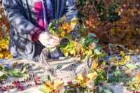 Woman attaching bundles of Beech sprigs, Portuguese laurel sprigs, Teasel heads and Hawthorn twigs to wreath