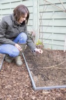 Woman placing birch sticks along the compost