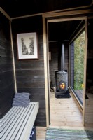 Timber black painted wood sauna cabin with a glass window view to the garden
