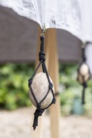 Large pebble in black string net hanging from table cloth